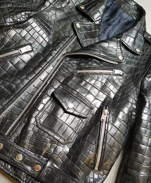 Close-up of a black crocodile-patterned leather jacket with zippers.