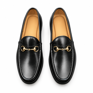 Pair of men's black leather loafers with gold bit, top-down view